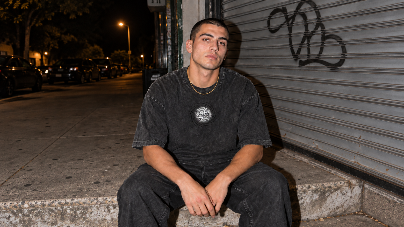 Model im schwarzen IONIC Spiral Wash Tee im Washed-Look mit Goldkette
